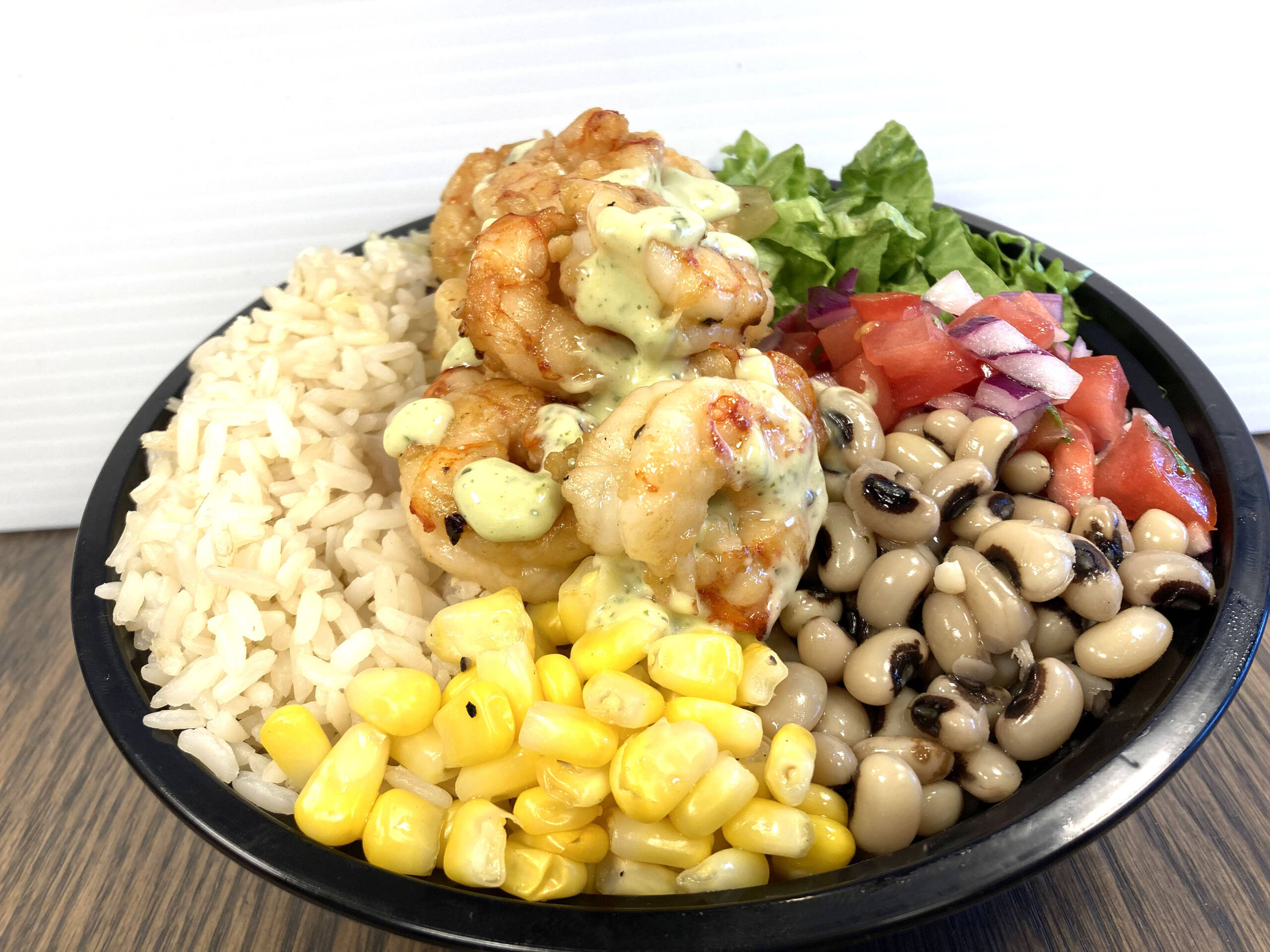 Grilled shrimp bowl served with Mediterranean Rice, Romaine Lettuce, Corn, Black Eyed Beans, Diced Tomato, Diced Red Onions, Cilantro, and Fresh Herb & Cream Sauce