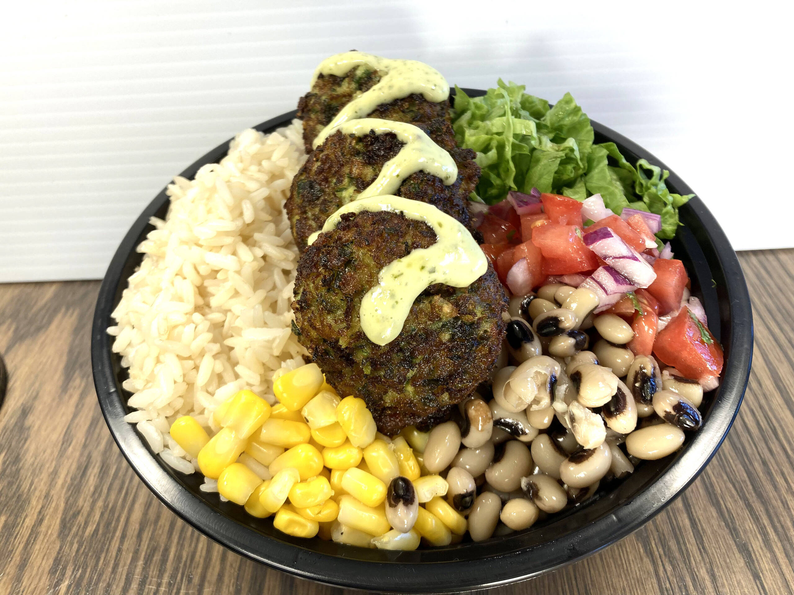 Grilled zucchini bowl served with Mediterranean Rice, Romaine Lettuce, Corn, Black Eyed Beans, Diced Tomato, Diced Red Onions, Cilantro, and Fresh Herb & Cream Sauce